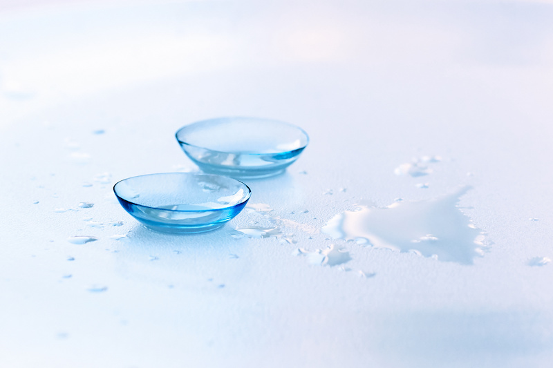 Contact lenses and water drops on light blue background. Buy your contact lenses online from https://www.onlinelenses.com.au